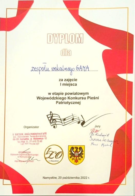 Dyplom za zajęcie I miejsca w etapie powiatowym Wojewódzkiego Konkursu Pieśni Patriotycznej. Czerwone wstęgi na białym tle.